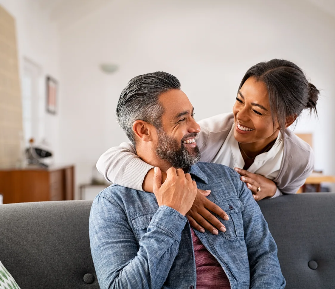 A happy couple smiling together at home after oral surgery care